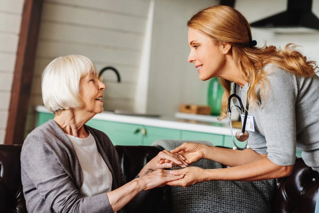 support worker holding hands with an elderly lady