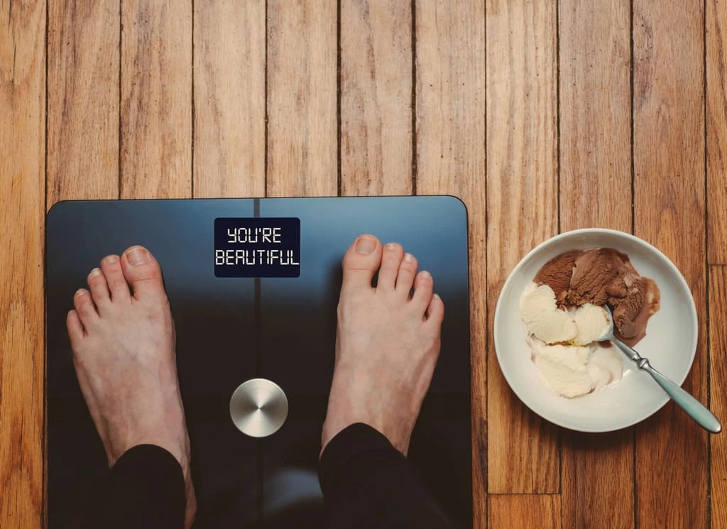 feet of a man standing on a scale that shows "you're beautiful" sign