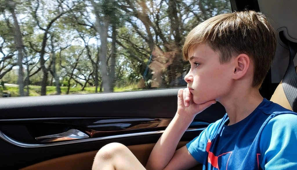 kid looking through a car window thinking
