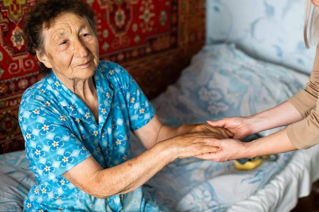 caregiver holding elderly woman's hands
